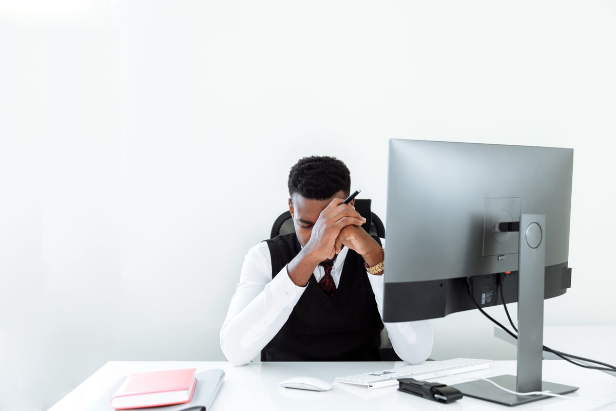 Stressed businessman with his head in his hands at his office desk